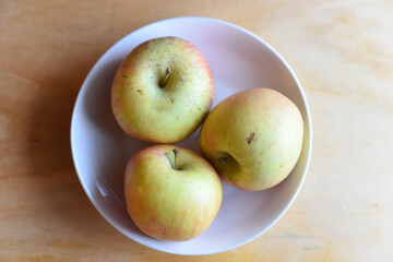 Fresh Apples in the Plate on Wooden Table
