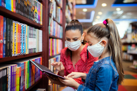 Mother And Daughter With Face Mask Shopping In Bookshop, Coronavirus Concept.