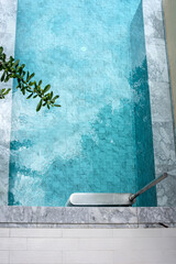 Top view of a family turquoise private swimming pool with a sunlight during the afternoon.