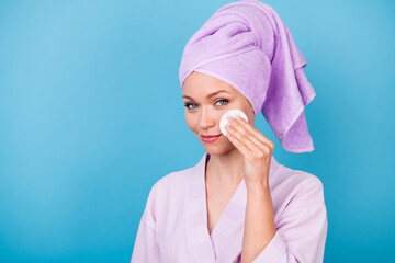 Photo of charming woman hand hold white sponge cheekbone wear violet towel turban bath robe isolated blue color background