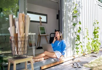 Mature woman working in home office in container house in backyard.
