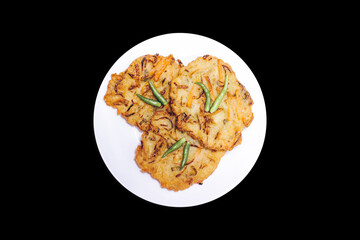 Bakwan is a typical Indonesian fry consisting of vegetables and dough with green chilies on top. served on a white plate on a dark background.
