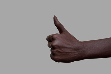 The sign of the thumb. A hand with black skin showing the like sign on a gray isolated background....