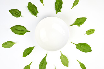 Green spinach leaves placed around the white empty bowl