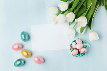 Easter greeting card with colorful easter eggs on blue background. Top view, flat lay with space for your text.