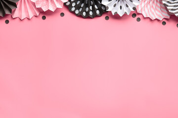 Paper fans on pink background, top view, copy-space. Celebration background in pink, black, white.