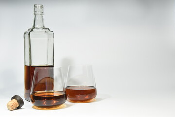 Half filled decanter bottle with two glasses and a bottle cork