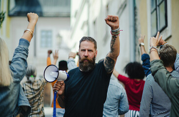 Portrait of man with megaphone protesting on streets, strike and demonstration concept.