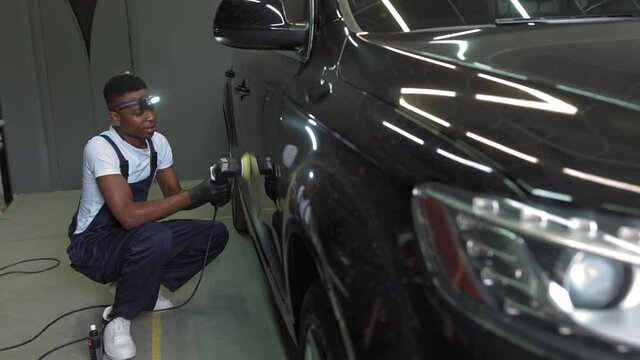 A young African-American polishes a car.Car detailing - Men are using machinery car polishers maintenance to remove marks repair according to the surface of the car's paint before continuing to coat