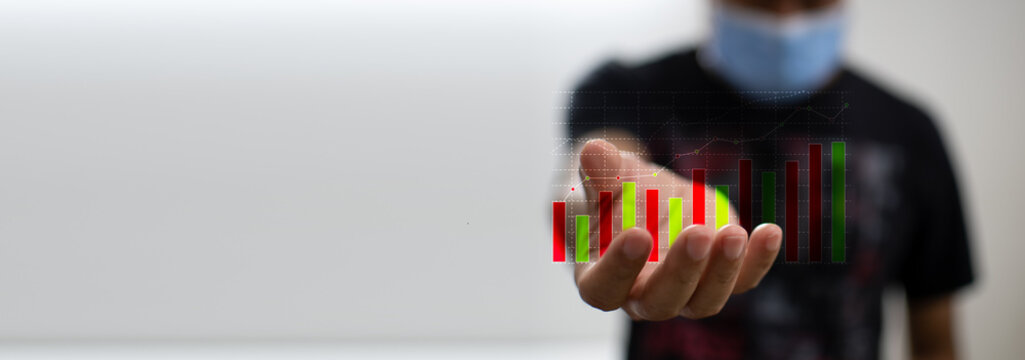Colored graphs show market movements in men's hands in a day off and wear a mask to prevent the coronavirus or COVID-19, take a close-up shot with a white and blurred background