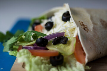 Vegetarian wrap made of cheese, onion, olives and salad close-up
