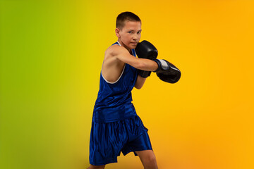 Competitive. Teenage professional boxer training in action, motion isolated on gradient background...
