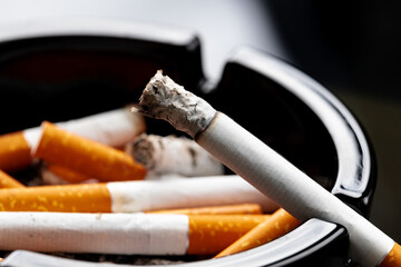 Burning cigarette in a black ash tray