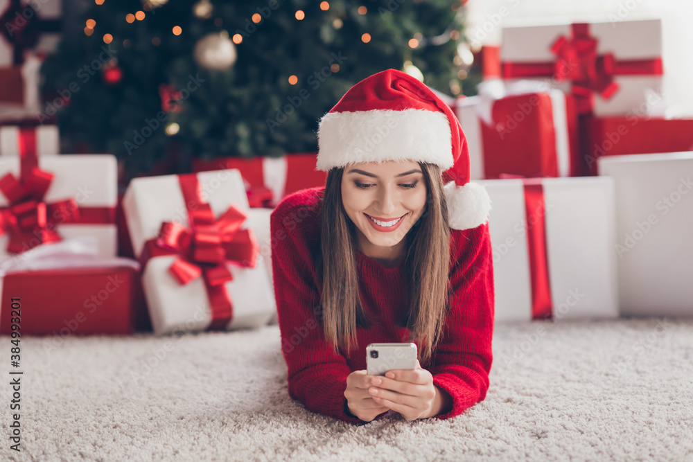 Poster Charming girl lie floor carpet hold telephone wear santa headwear red sweater in decorated x-mas living room indoors