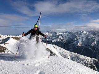 Ski touring in mountains. High alpine landscape. Ascent and descent to a summit of an alpine peak. Snow and winter activities, skitouring in mountains.