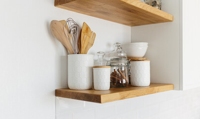 Kitchen shelves with various white ceramic and glass jars.