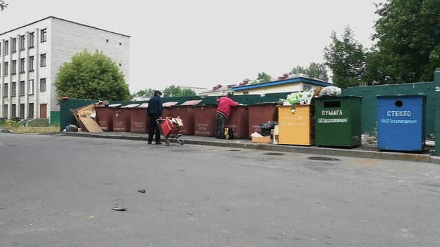 Beggars, tramps, and poor men collecting and sorting garbage in public waste containers, trash tanks in summer. Hobo. Poverty and survival for Homeless people