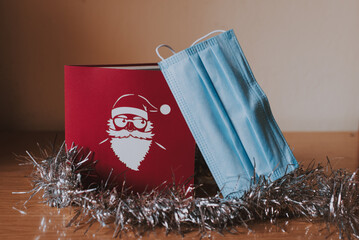 Una tarjeta roja de navidad con un Santa Claus blanco al lado de un espumillón plateado y una...