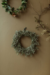 Round homemade wreath frames made of fir needles and branches on olive wall. Christmas / New Year celebration decorations.