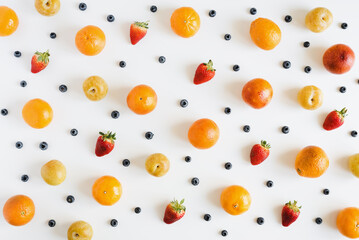 Friuts and berries on white background, overhead view. Fruit pattern. Yellow plum, strawberry, blueberry and orange