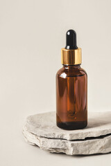 One brown bottle of cosmetics on a natural gray background. Stone podium. Front view.