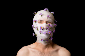 a portrait of a guy his head is wrapped in a bandage, flowers stick out of the bandage