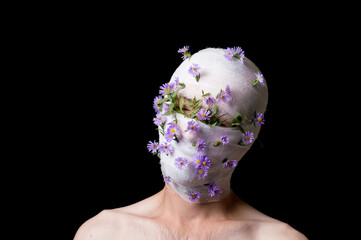 a portrait of a guy his head is wrapped in a bandage, flowers stick out of the bandage