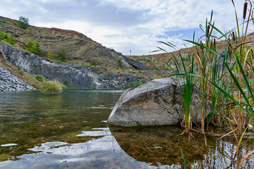 Lake in an ancient quarry with various types of rocks