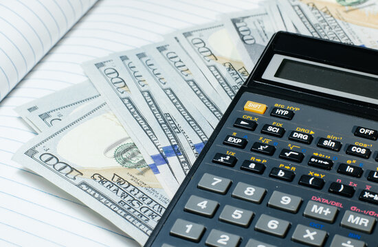 Top close up view of a photo of a calculator lying on the desktop on a pile of money.
