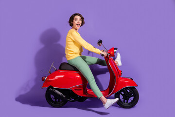 Fototapeta na wymiar Full length body size side profile photo of female millennial with bob hair driving red scooter smiling isolated on bright purple color background