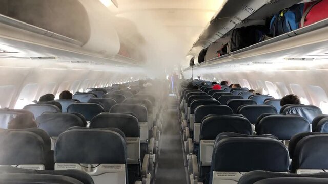 View of a plane's corridor full of fog. Shot of the corridor of an airplane full of smoke. Shot of interior of a plane with the air conditioning during a flight.