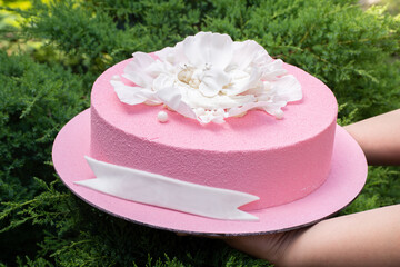 Festive pink cake with a sculpture of an angel on a white flower