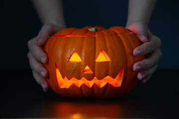 Women’s hands hold a scary pumpkin. Halloween