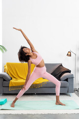 Afro woman doing the reverse Warrior pose at home