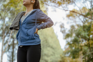 A woman stands to breathe in natural air after jogging.Nature park. Healthy and Lifestyle Concept.