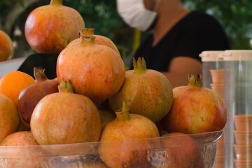 ripe pomegranate fruits prepared for fresh juice on blurred open air cafe background