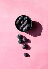 Plums isolated on pink background. Still life photography. Fruit pattern. Minimal, colorful photography.