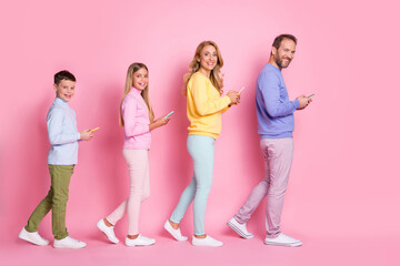 Obraz premium Full body profile side photo of dad mom small kids go with cell phone isolated over pink pastel color background