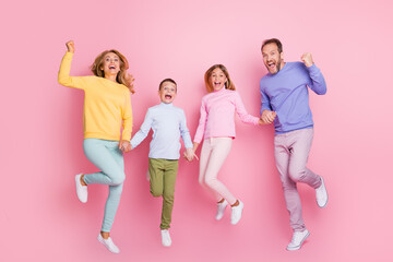 Full length photo of ecstatic mommy daddy small kids jump hold hands raise fists isolated on pastel...