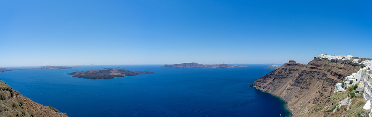 Beautiful panoramic view from Thira to caldera and volcano on a sunny day. Picturesque natural background with copy space for text. Santorini island, Cyclades, Greece, Europe.