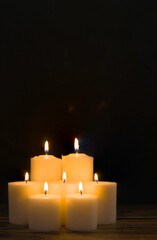 Group of seven burning candles with black background. Concept of comfort, spirituality, mysticism, religion, remembrance of the dead. Day of the Dead. Vertical photography with copy space