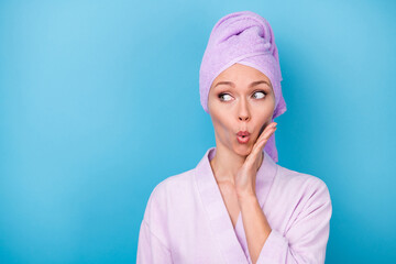 Photo of cute girl hand cheekbone funny face look empty space wear purple towel turban bath robe isolated blue color background