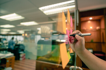 Hand writing paper note, sticky note on glass window with close up shot.