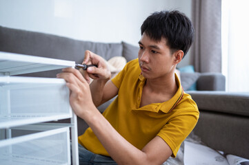 Asian men assembling furniture in the living room at home.