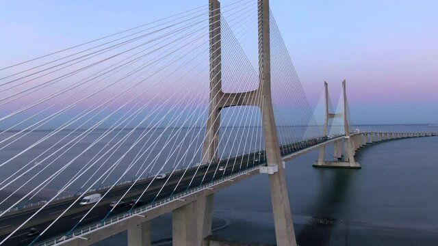 Aerial jib shot showing traffic on architectural landmark Vasco da Gama Bridge at twilight in Lisbon, Portugal. The Vasco da Gama Bridge is the longest bridge in the European Union.