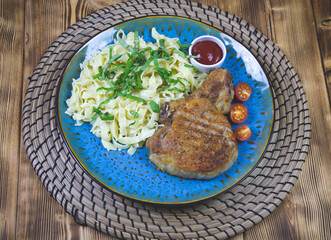 Grilled pork steak with bone in sweet honey glaze and pasta and fresh vegetables close-up on a plate on the table. horizontal