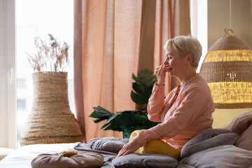 Senior woman practicing yoga at home, making Alternate Nostril Breathing exercise, nadi shodhana...