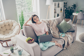 Photo portrait of woman coming up with new ideas with laptop sitting on sofa indoors