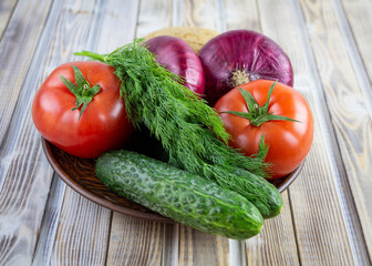On a plate are vegetables, tomatoes, cucumbers, onions and dill. Fresh vegetables close-up. Natural food.