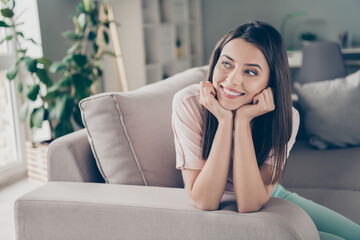 Photo portrait of young girl sitting on couch thinking dreaming holding face with hands indoors